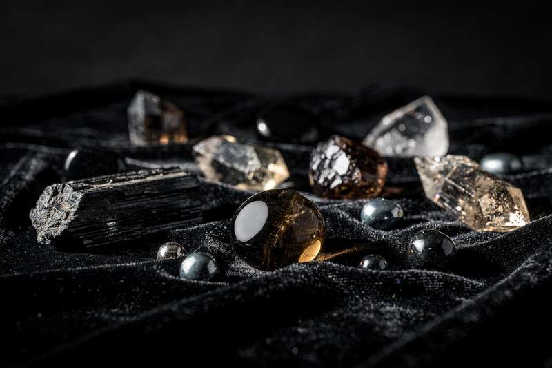 Conjunto de piedras naturales de varios colores dispuestas sobre una superficie de madera para la limpieza energética y...