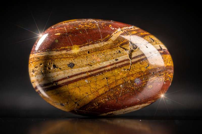 Piedra de Mookaita con tonalidades rojizas y amarillas mostrando sus patrones naturales característicos.