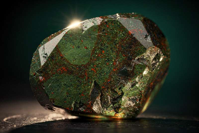 Piedra de sangre roja oscura pulida que irradia energía de fuerza y vitalidad en un entorno natural.