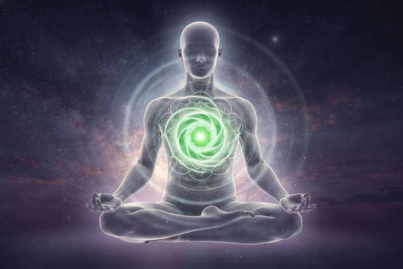 Representación del chakra cardíaco Anahata en el centro del pecho humano irradiando luz verde y rosa.
