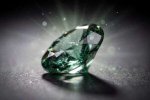 Esmeralda verde tallada junto a otros cristales minerales sobre superficie de madera natural.