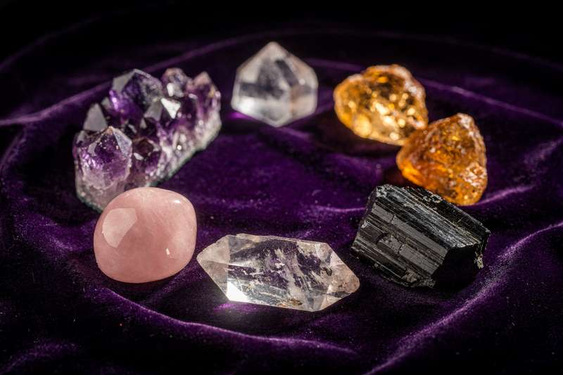 Colección de piedras naturales brillantes en tonos variados dispuestas sobre una superficie de madera clara para iniciarse en...