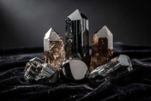 Piedras naturales de color negro y violeta dispuestas sobre una superficie de madera para representar amuletos de protección.